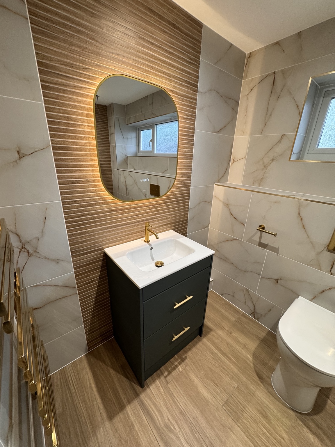 Finished Calypso bathroom with backlit mirror, vanity and brass fittings