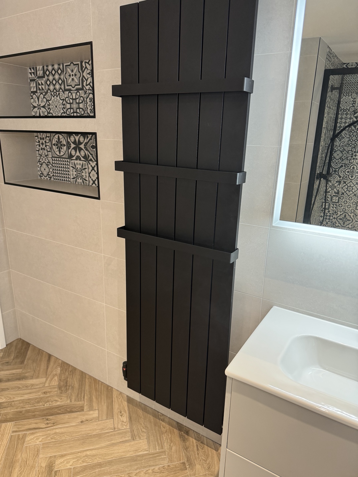 Tall black radiator with towel bars installed by SMC