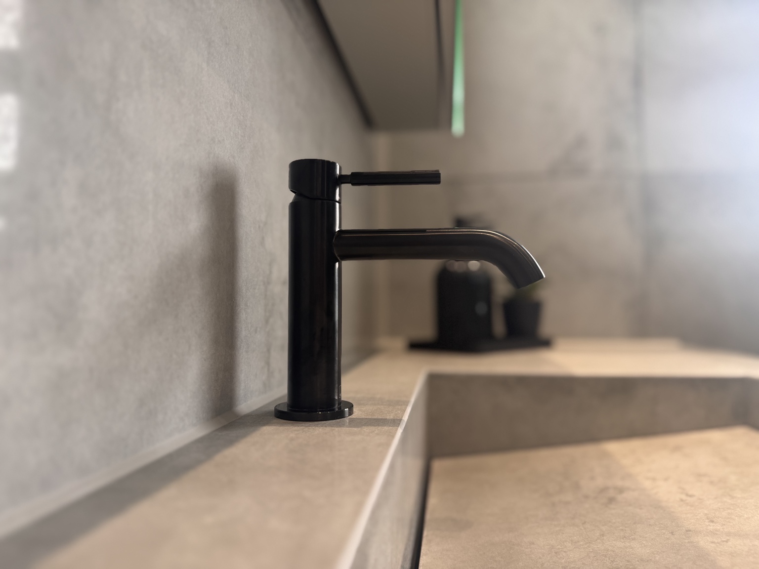 Close detail of the black basin tap and tile finish